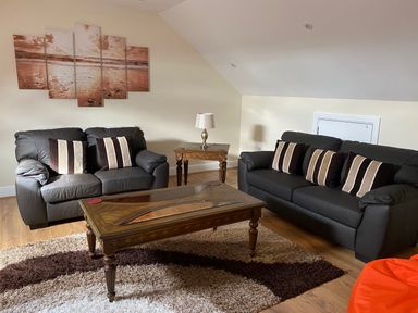 A living room with two leather sofas and a wooden coffee table at Llygad Yr Haul Sun in Burry Port