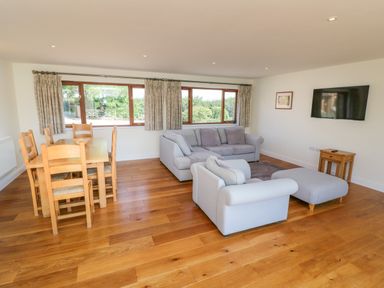 A living room with sofas a dining table and chairs and a television on the wall at Little Owl Barn in Upton Snodsbury