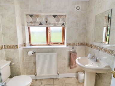 A bathroom with a toilet sink mirror window and towel at Little Owl Barn in Upton Snodsbury