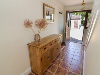 A hallway with a wooden cabinet and vase with dried flowers at Little Owl Barn in Upton Snodsbury