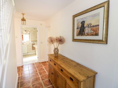 A hallway with a wooden sideboard vase with dried flowers and a framed picture of two dogs at Little Owl Barn in Upton Snodsbury