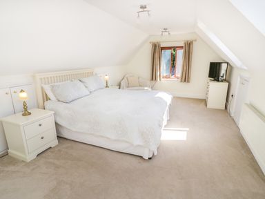 A bedroom with a double bed nightstands a chair a window and a television on a dresser at Little Owl Barn in Upton Snodsbury