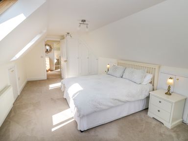 A bedroom with a bed two bedside tables and lamps under sloped ceilings at Little Owl Barn in Upton Snodsbury