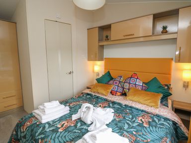 A bedroom with a bed featuring a tiger print bedspread and multiple pillows at 95 Hafan Taffy in Gilfachrheda near Llanarth