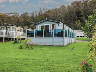 A mobile home with a fenced patio in a grassy area with trees at 95 Hafan Taffy Gilfachrheda near Llanarth
