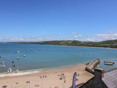 A beach with people and boats on the water at 95 Hafan Taffy in Gilfachrheda near Llanarth