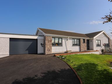 A single story house with a garage driveway and lawn at Corrie Knowe in Trearddur Bay