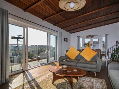 A living room with a brown wooden coffee table and grey sofas with yellow cushions at Corrie Knowe in Trearddur Bay