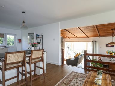 An open kitchen and living area with wooden bar stools and a wooden ceiling at Corrie Knowe in Trearddur Bay