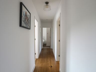 A hallway with wooden floor and white walls with an octopus picture on the wall at Corrie Knowe in Trearddur Bay