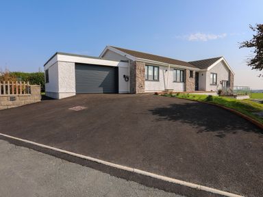 A single story house with a large driveway and a garage at Corrie Knowe in Trearddur Bay