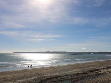 A beach with two people and a dog near the water at Harveys House in Helston