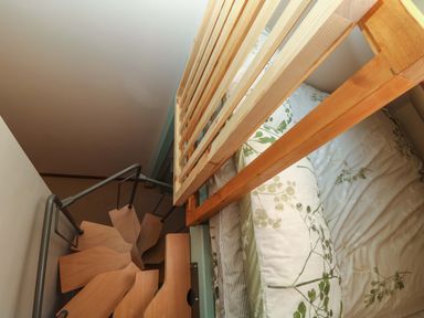 A small bedroom with a bed next to a wooden railing and a spiral staircase nearby at Harvey's House in Helston