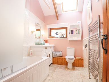 A bathroom with a bathtub a toilet a sink and towels at Harveys House in Helston