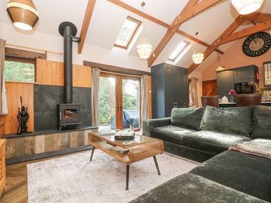 A living room with a woodburner stove green sofas and a wooden coffee table at Harveys House in Helston