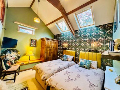 A bedroom with twin beds, floral wallpaper, wooden wardrobe, and skylight windows at Harveys House in Helston
