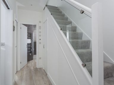 A hallway with carpeted stairs and an open door leading to a bathroom at Chy Lowen in Porthleven