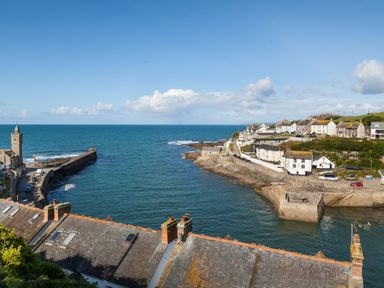 A coastal harbor with a clock tower and buildings along the shore at Chy Lowen in Porthleven