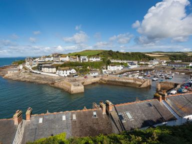 A coastal village with houses boats and a harbor under a blue sky at Chy Lowen in Porthleven