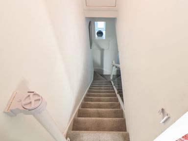 A staircase with carpeted steps and glass railing at Chy Lowen in Porthleven