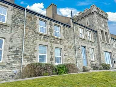 Stone building with multiple windows blue door bench and manicured lawn at Chy Lowen in Porthleven