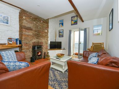 A living room with leather sofas wood burning stove and a view of the sea at 2 Bayview in Torcross