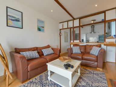 A living room with two brown leather sofas and a white coffee table at 2 Bayview in Torcross