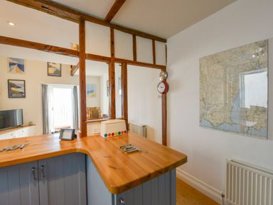 A kitchen counter with a clock on the wall and a framed map at 2 Bayview in Torcross