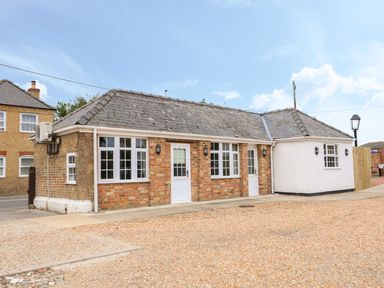 A single-story brick building with white doors and windows on a gravel area at The Five Bells Inn in Upwell