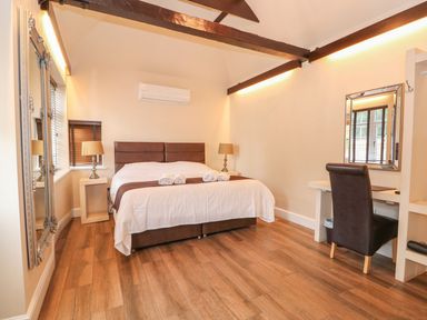 A bedroom with a double bed a desk with a chair two lamps and a large mirror at The Five Bells Inn in Upwell