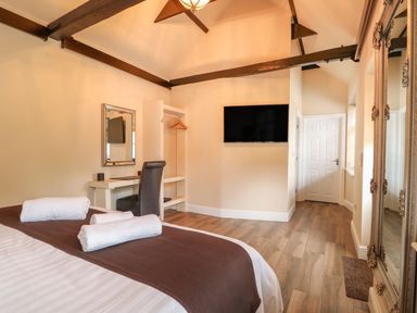 A bedroom with a bed folded towels a desk chair a wall mirror a mounted television and wooden floor at The Five Bells Inn in Upwell