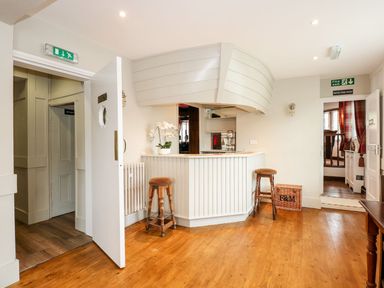 A reception area with a white counter wooden stools and a wicker basket at The Five Bells Inn in Upwell