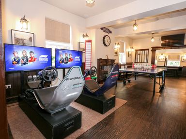 A gaming room with two racing simulator seats and screens and a ping pong table at The Five Bells Inn in Upwell