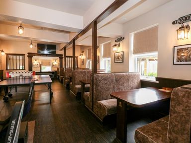 A game room with a ping pong table and foosball table and booth seating at The Five Bells Inn in Upwell