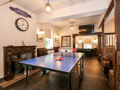 A game room with a ping pong table foosball table and seating booths at The Five Bells Inn in Upwell