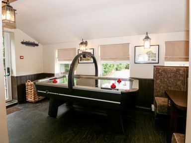 A room with an air hockey table a wicker basket wall lamps and booth seating at The Five Bells Inn in Upwell