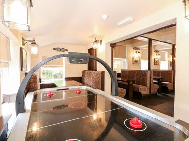 An air hockey table in a room with booth seating and tables at The Five Bells Inn in Upwell