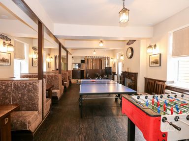 A game room with a ping pong table foosball table and booth seating at The Five Bells Inn in Upwell