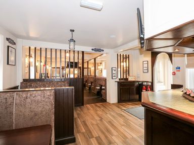 An indoor seating area with booth-style benches and a bar counter at The Five Bells Inn in Upwell