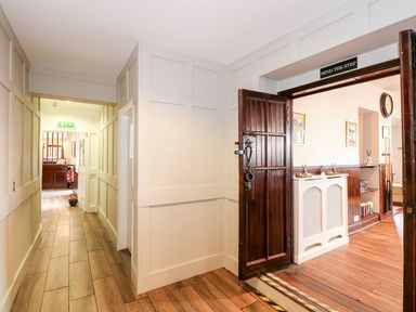 A hallway with wooden flooring and cream paneled walls next to an open dark wooden door with a step and a sign saying mind the step at The Five Bells Inn in Upwell