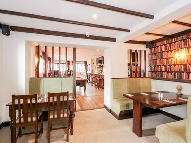 A dining area with wooden tables and chairs next to a room with a pool table and bar at The Five Bells Inn in Upwell