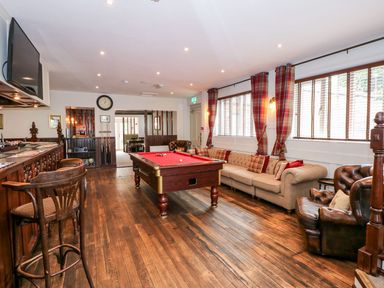 A recreational room with a pool table wooden bar stools and a sofa at The Five Bells Inn in Upwell