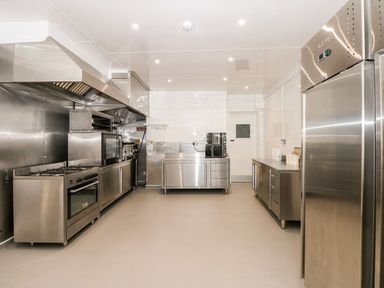 A commercial kitchen with stainless steel appliances counters and refrigerator at The Five Bells Inn in Upwell