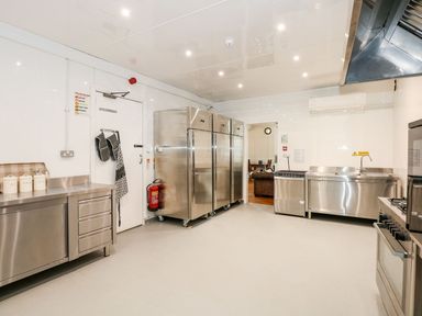 A commercial kitchen with stainless steel appliances including refrigerators a sink a dishwasher and an oven at The Five Bells Inn in Upwell