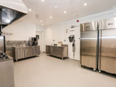 A commercial kitchen with stainless steel cabinets two refrigerators a stove and microwave ovens at The Five Bells Inn in Upwell