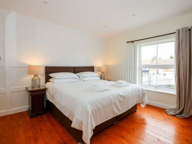 A bedroom with a double bed bedside tables lamps wooden floor and a window with curtains at The Five Bells Inn in Upwell