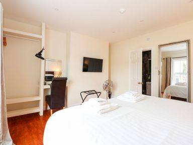 A bedroom with a bed a wall-mounted TV a desk with a chair and a mirror at The Five Bells Inn in Upwell