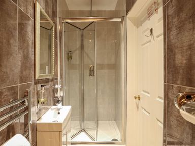 A bathroom with a shower enclosure, sink with mirror, towel rack, and closed door at The Five Bells Inn in Upwell