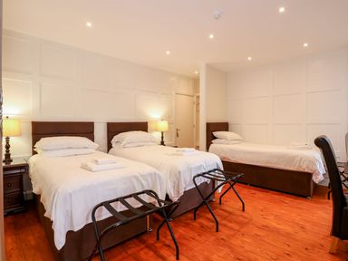 A bedroom with three single beds two bedside tables lamps and luggage racks at The Five Bells Inn in Upwell