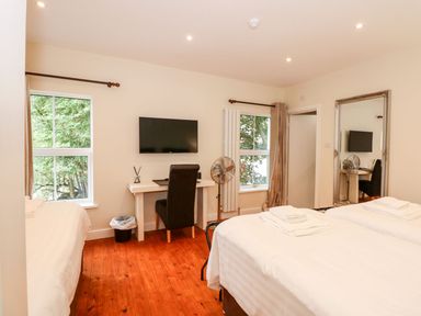 A bedroom with two beds a desk with a chair and a wall mounted TV at The Five Bells Inn in Upwell